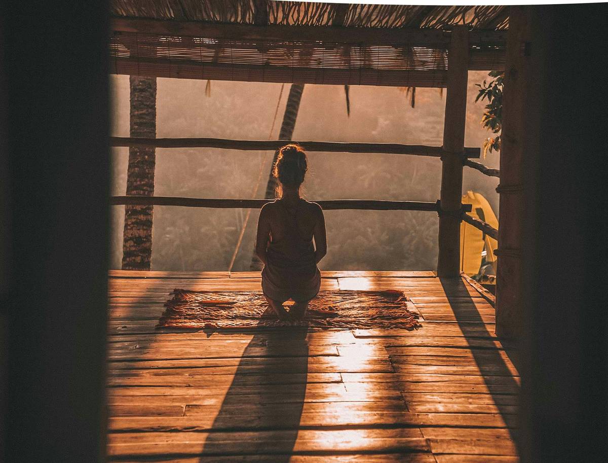 woman practicing meditation routine for beginners on a yoga mat at sunrise